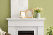 © Pixel-Shot - Blank photo frames, painting and vase with tulips on mantelpiece in living room