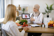 © sofiko14 - Beautiful adult woman at appointment with family nutritionist. Muslim experienced female doctor showing tablet with gastrointestinal tract image for treatment planning to mature lady.