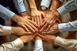 © Natalia - Close-up of multiple hands stacked together in a gesture of unity and teamwork