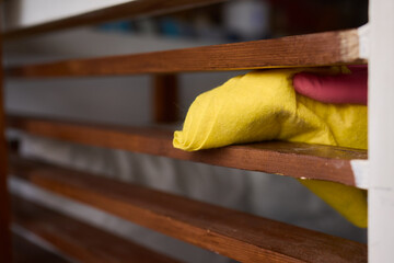Wall Mural - Person in pink gloves cleans wooden table with yellow cloth