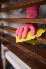 Wall Mural - Person in pink gloves cleans wooden table with yellow cloth