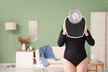 Canvas Print - Young overweight woman with weight scales at home