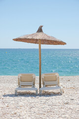 View to turquoise blue Mediterranean Sea and Albir seaside beach in Alicante province, Spain. Raco de Albir Beach with white pebbles, umbrellas and beach sun loungers in beautiful sunny day