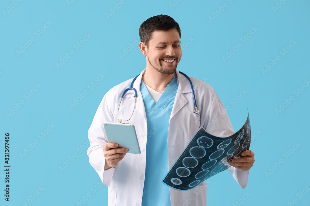 Male doctor with MRI scan and tablet computer on blue background