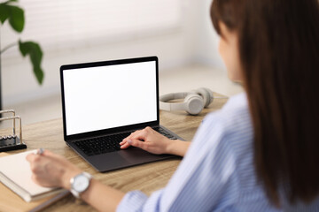 Poster - Woman taking notes during webinar at wooden table in office, selective focus