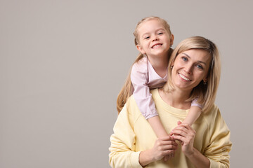 Canvas Print - Family portrait of happy mother and daughter on grey background. Space for text