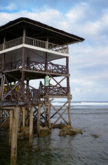 Wall Mural - Wooden bungalow with terrace on piles on the sea beach.