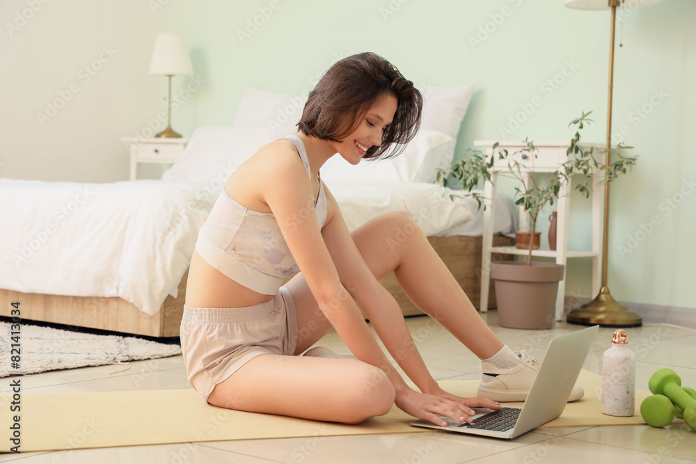 Sporty young woman using laptop in bedroom