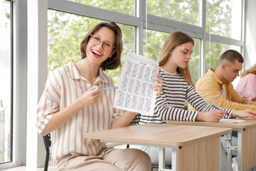 Poster - Happy female student with results of exam in classroom