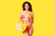 © Pixel-Shot - Beautiful young African-American woman in swimsuit with bottle of sunscreen cream on yellow background