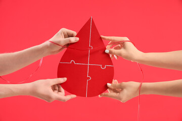 Wall Mural - people holding paper drop with tube on red background. Blood donation concept