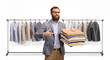 © Ljupco Smokovski - Man pointing at a pile of folded clothes in front of a rack with clothes on hangers