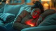 © Liana - A woman sleeps on a couch, illuminated by a warm red light emanating from her chest, creating a cozy nighttime ambiance.