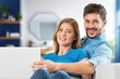 © BillionPhotos.com - Happy young couple with laptop relaxing at home.