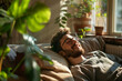 © Duka Mer - A man, sitting in his living room, smiles and enjoys the sun, with natural light from the window and plants on the side.