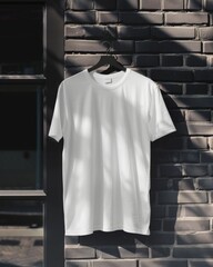 Wall Mural - A white blank t-shirt hangs against a dark brick wall in sunlight, ideal for fashion mockups