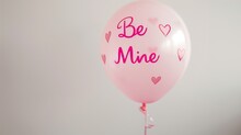A Pastel Pink Balloon With The Phrase "Be Mine" Written In A Playful, Hand-drawn Font, The Gentle Color And Sweet Message Creating A Romantic And Inviting Image Against The White Surroundings.