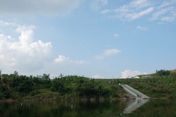 a portrait of a reservoir in a village with calm water and green scenery 