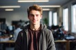 © vefimov - A young man is smiling and wearing a gray hoodie. He is standing in front of a window with a potted plant in the background