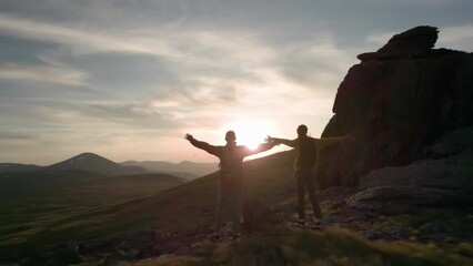 Aufkleber - Two active hikers walks high in mountains at sunset time. Silhouettes of tourists are walking at mountain top