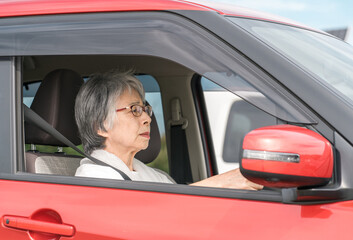 Sticker - 自動車の運転をする不安な表情の高齢者ドライバーの女性
