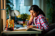 © StockImageFactory - Asian Indian girl child studying at home on study table with computer, books, Globe model, victory trophy
