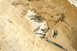 © evgenia_lo - Aerial view of a large-scale sand portrait on a beach, with a person standing next to the artwork for scale.