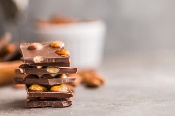 Poster - Broken chocolate bar with almonds on kitchen table.