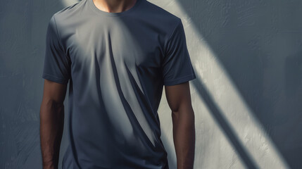 Wall Mural - Man Wearing a Grey T-Shirt Stands in Sunlight with Gray Wall Background., Mockup