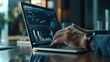 © Антон Сальников - A close-up of hands of a Caucasian male professional in a business research and development company, reading financial reports and looking at graphs and charts on a laptop computer
