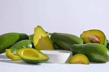 Wall Mural - A lot of avocado cut in halves surrounded a round podium. White background. Avocados can also help eliminate inflammation in the body