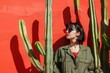 © AIGen - Trendy Plants. Happy Woman in Stylish Fashion with Cactus Plants by Red Wall