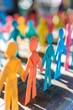 © Vuk - Vibrant paper cutouts of human figures holding hands under bright light expressing unity, community, and cooperation