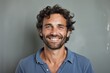 © Markus Schröder - Portrait of a cheerful man in his 30s smiling at the camera in front of bare concrete or plaster wall