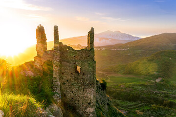 Wall Mural - immersive landscape of old castle ruins on foreground and beautiful mountains with sunset with clouds on background