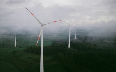 wind turbine blades at wind farm with trees on the field