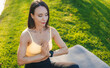 © Strelciuc - Woman in the park doing yoga, meditation on a yoga mat, taking care of her body and mental health.