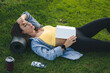 © Strelciuc - Brunette woman laying on the grass and falling asleep while she was reading a book.Tired after morning workout.