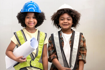 African boy and girl wearing a reflective vest stands and smile over white wall, girl holding a scroll And the paper