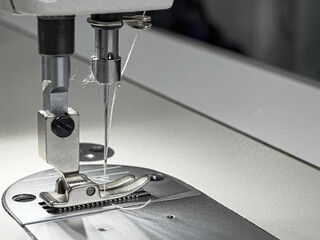 Close-up of a part of a sewing machine with a needle in which thread is threaded, for sewing clothes, for industry, for households.