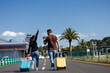 © Paula - Couple arriving at the airport with their suitcases to go on vacation. Young people walking to the airport to visit their family or friends.