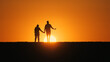 © StockMediaSeller - Holding hands, a young couple walks together across a field, moving towards the setting sun.