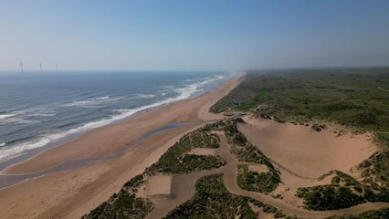 Wall Mural - offshore wind farm revealed in north sea on horizon, grassy sand dunes remain untouched in foregroun