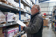 © Nedrofly - A man stands in an industrial warehouse, holding a piece of paper in his hand