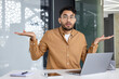© Tetiana - Confused young man in office with laptop, unsure expression and hand gesture