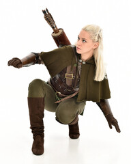 Canvas Print - full length portrait of blonde female model wearing green fantasy elf warrior halloween costume with leather armour. sitting pose kneeling. isolated on white studio background.