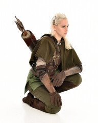 Wall Mural - full length portrait of blonde female model wearing green fantasy elf warrior halloween costume with leather armour. sitting pose kneeling. isolated on white studio background.