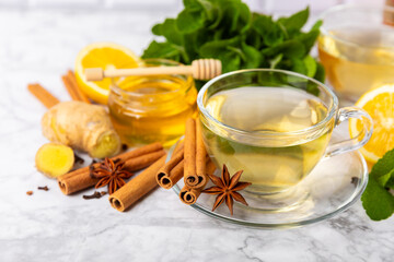 Wall Mural - Fragrant hot tea with cinnamon stick and anise on a textured wooden background. A cup of hot tea with honey, lemon, mint and apples. Spicy tea with spices. Immunity tea. Health concept.Copy space.