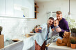 © Marko Geber - Two dads and toddler son taking a selfie in kitchen