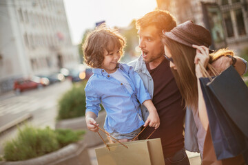 Wall Mural - Young family with child on city street holding shopping bags